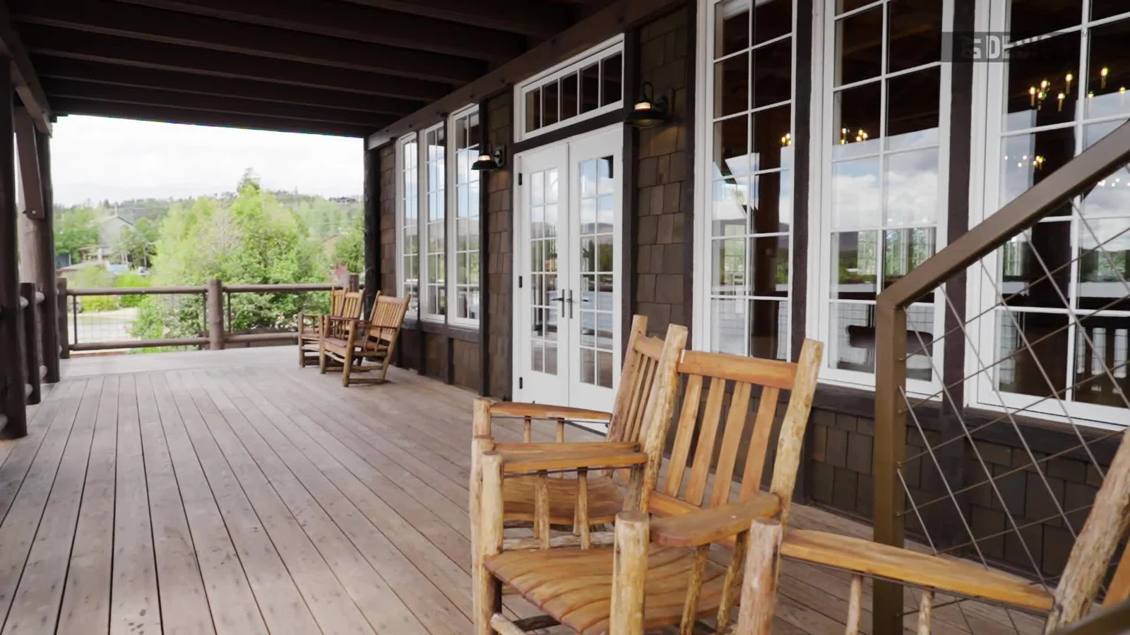 Wood decking beneath the covered porch, beside timber columns and rocking chairs at Grand Lake Yacht Club